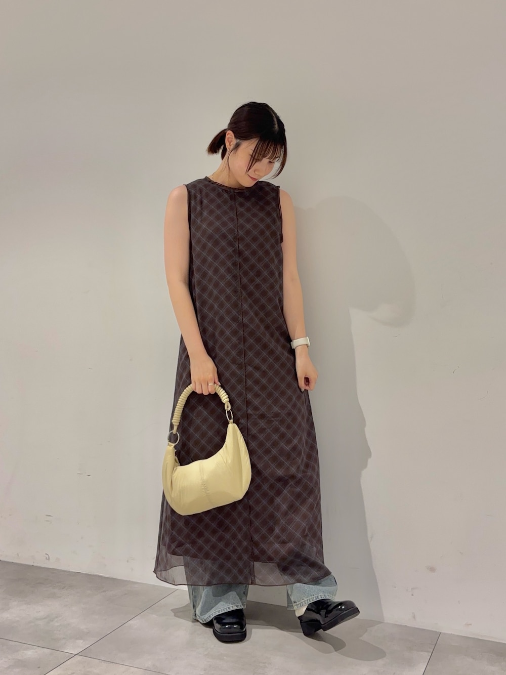ブラウン系のワンピース、ブルー系のデニムパンツ、ベージュ系のハンドバッグを着用したレディースの春コーディネートの1枚目の写真