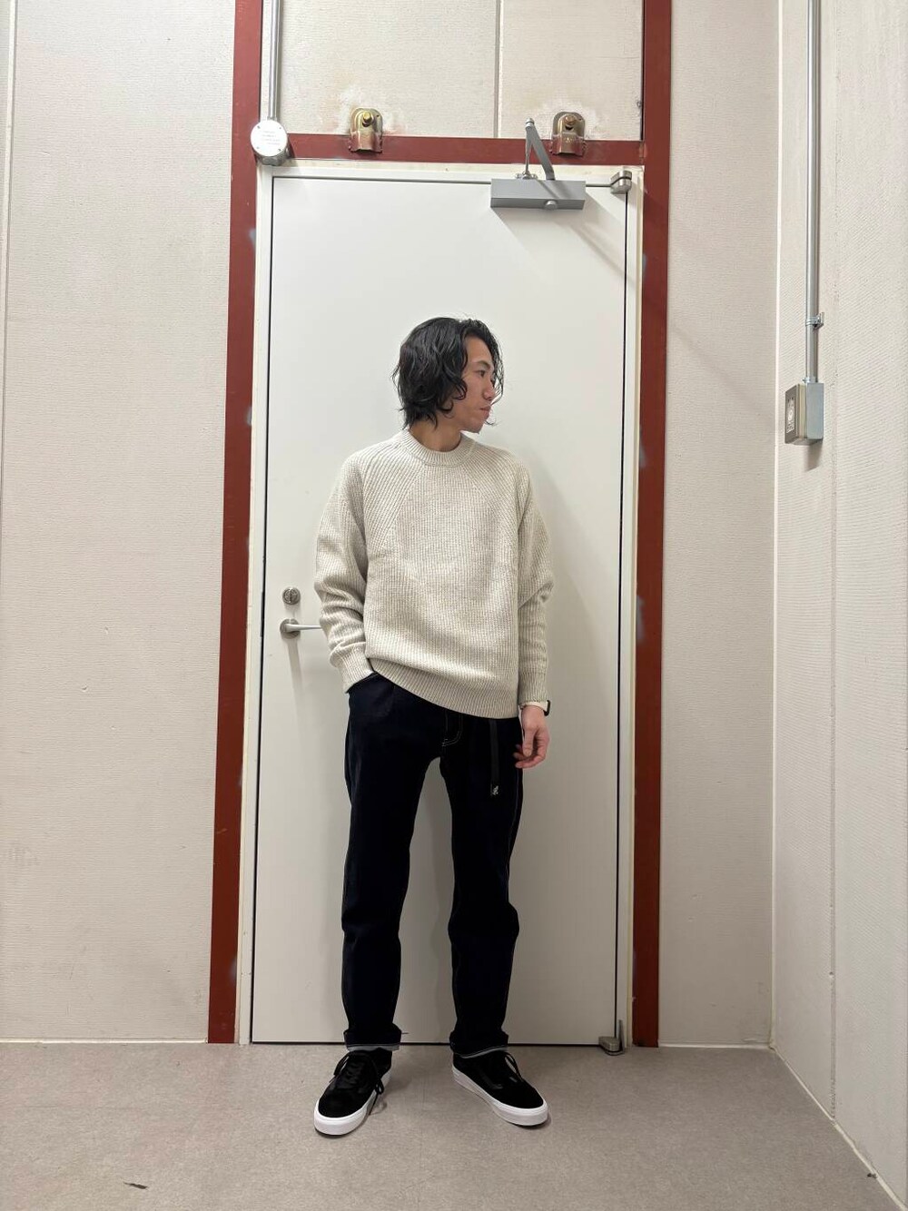 ブルー系のデニムパンツ、ホワイト系のニット/セーター、ブラック系のスニーカーを着用したメンズの冬コーディネートの1枚目の写真