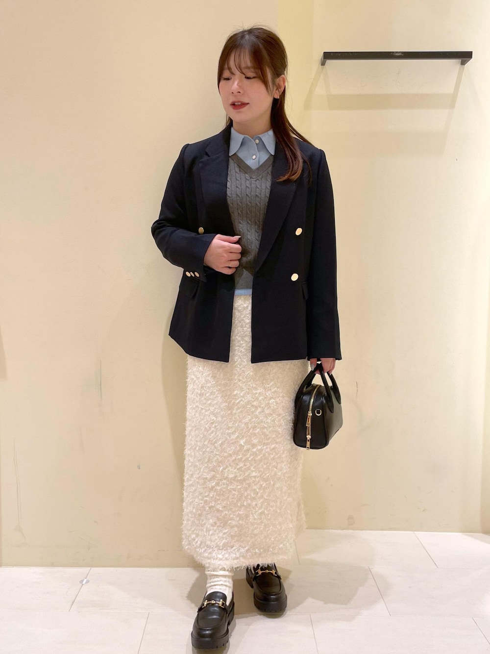 ブラック系のショルダーバッグ、ホワイト系のスカート、ブラック系のローファーを着用したレディースの秋コーディネートの1枚目の写真