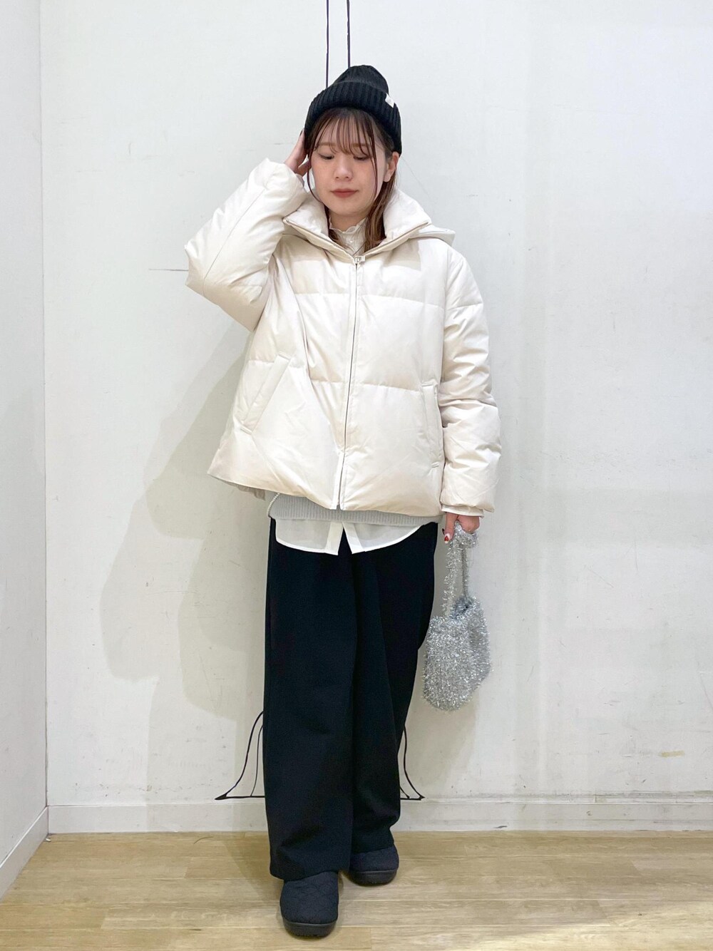 ベージュ系のダウンジャケット/コート、シルバー系のショルダーバッグ、ブルー系のニット/セーターを着用したレディースの冬コーディネートの1枚目の写真