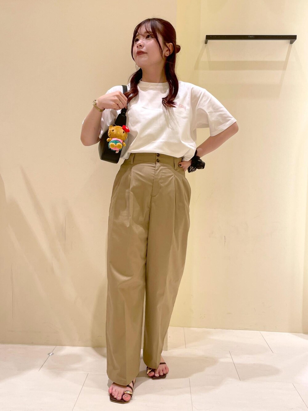 ベージュ系のチノパンツ、ブラウン系のサンダル、ブラック系のハンドバッグを着用したレディースの夏コーディネートの1枚目の写真