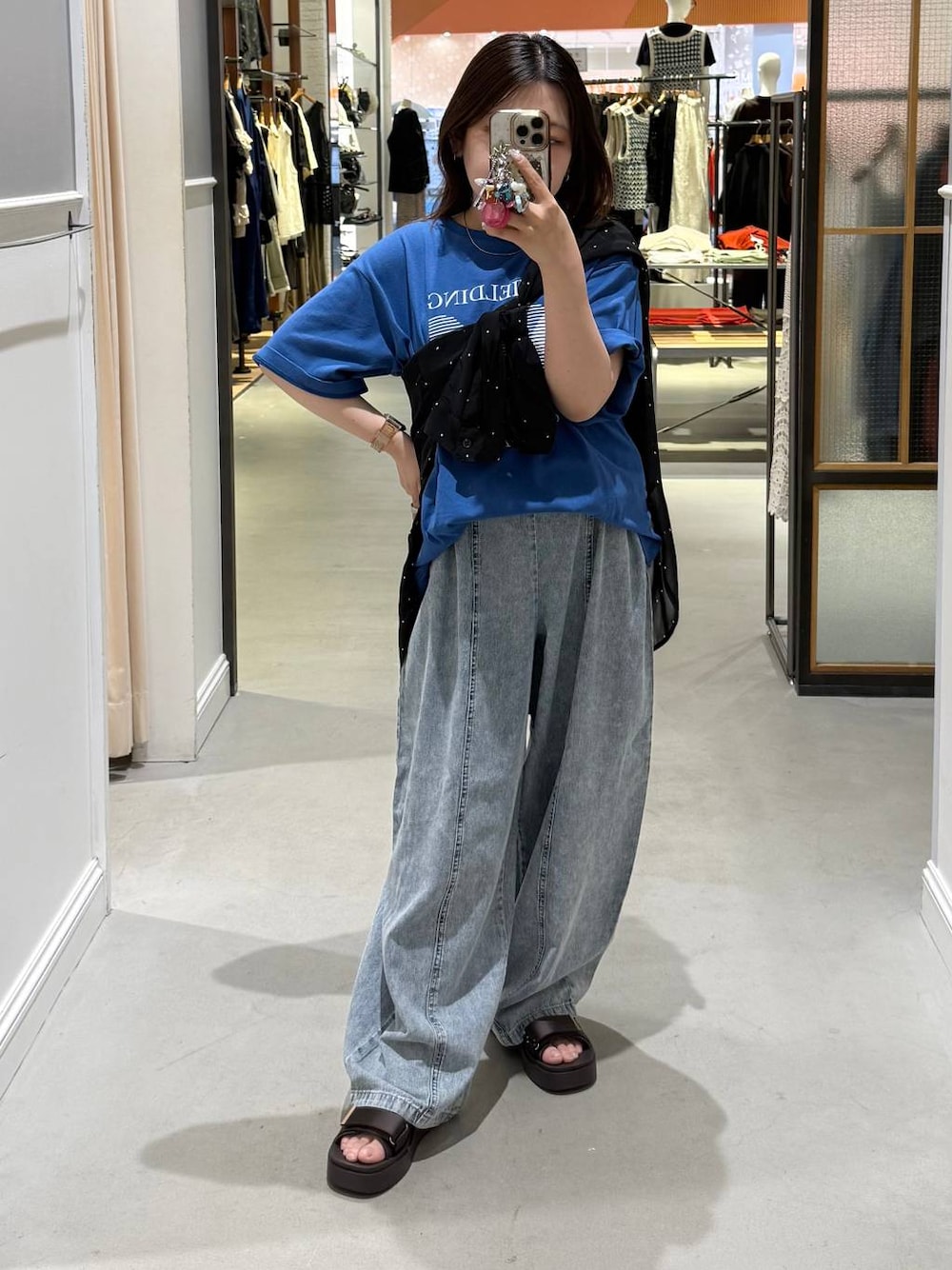 ブルー系のデニムパンツ、ブラック系のシャツ/ブラウス、ブラウン系のサンダルを着用したレディースの夏コーディネートの1枚目の写真
