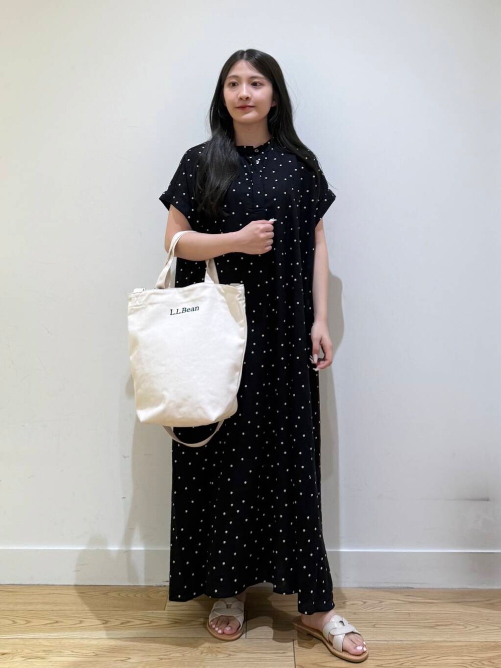 ホワイト系のサンダル、ブラック系のワンピースを着用したレディースの夏コーディネートの1枚目の写真