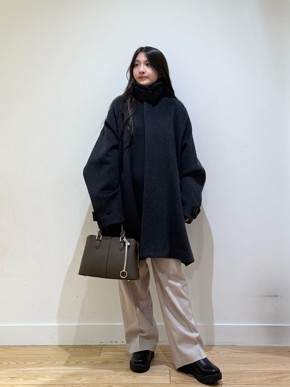 グレー系のステンカラーコート、パープル系のハンドバッグ、ベージュ系のその他パンツを着用したレディースの秋コーディネートの1枚目の写真