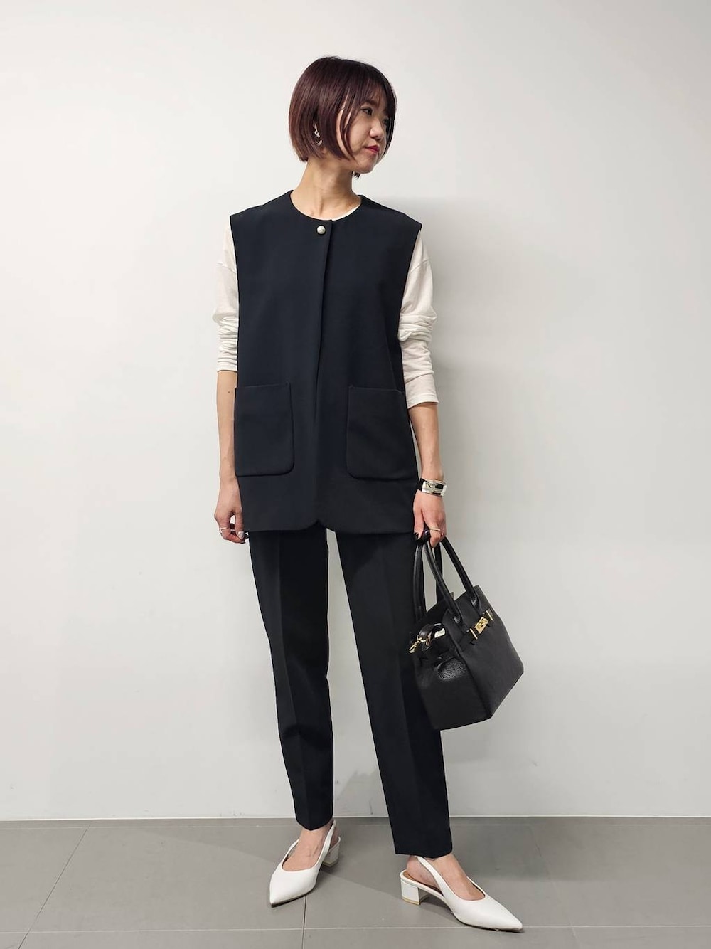 ホワイト系のTシャツ/カットソー、ブラック系のベスト、ブラック系のその他パンツを着用したレディースの冬コーディネートの1枚目の写真
