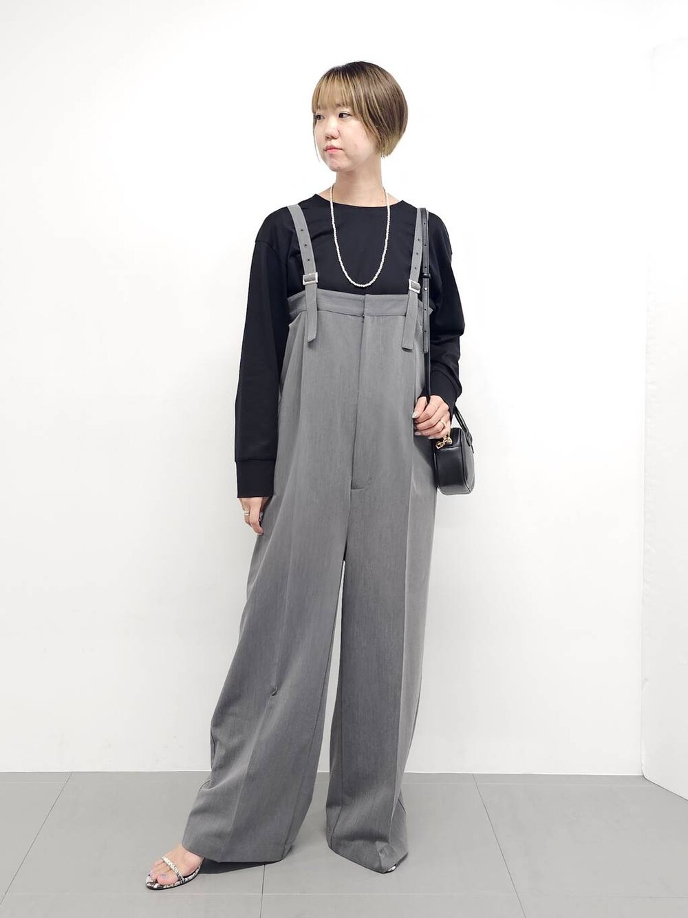 グレー系のサロペット/オーバーオール、その他のサンダル、ブラック系のTシャツ/カットソーを着用したレディースの秋コーディネートの1枚目の写真