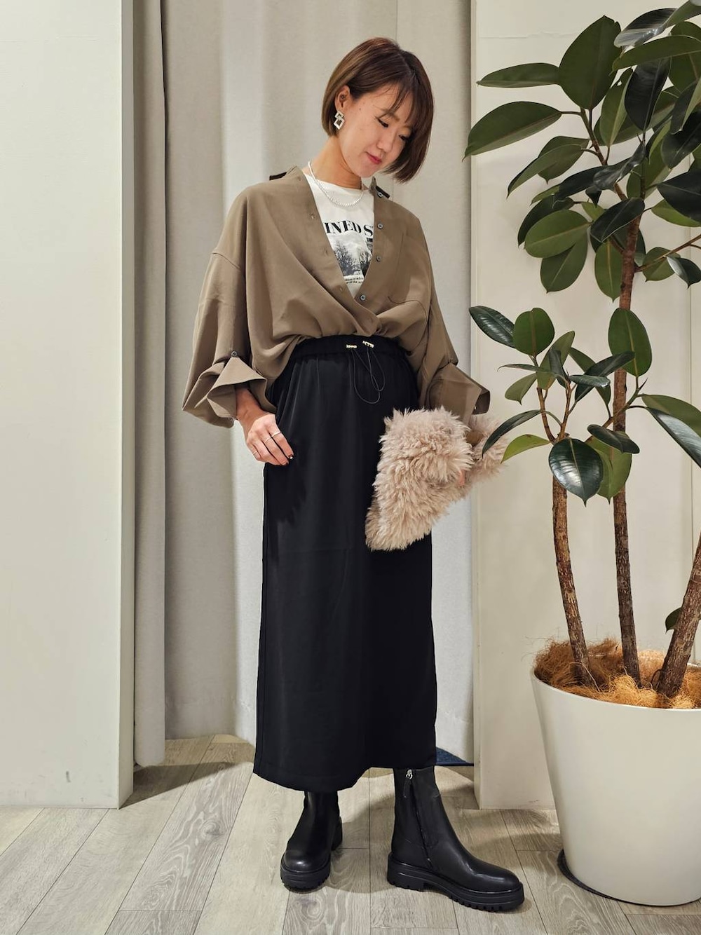グリーン系のシャツ/ブラウス、ホワイト系のTシャツ/カットソー、ブラック系のスカートを着用したレディースの秋コーディネートの1枚目の写真