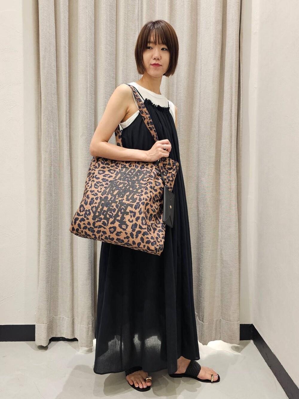 ブラック系のサンダル、ブラック系のワンピース、ホワイト系のTシャツ/カットソーを着用したレディースの夏コーディネートの1枚目の写真