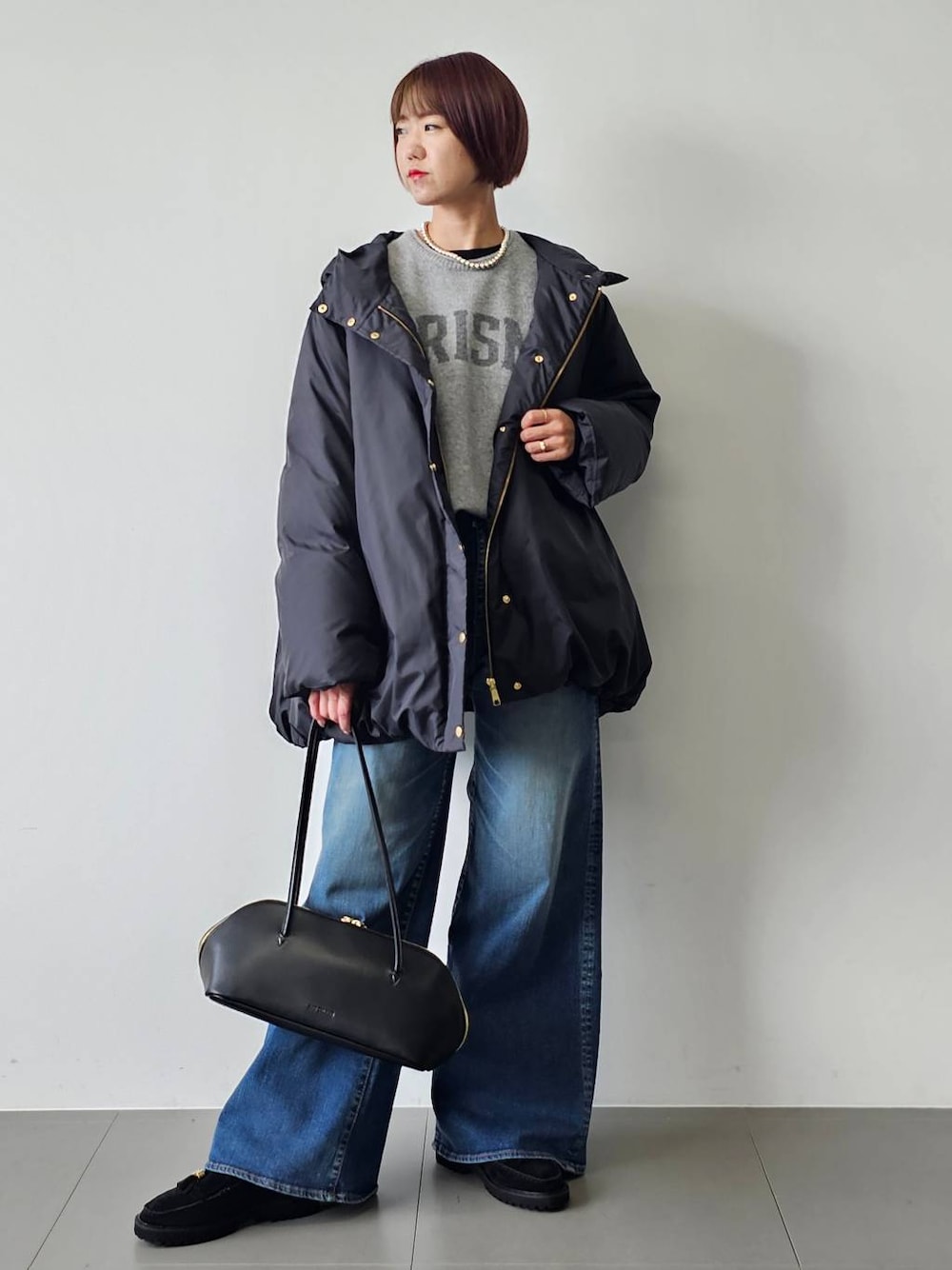 ブラック系のトートバッグ、ブラック系のTシャツ/カットソー、ブラック系のダウンジャケット/コートを着用したレディースの秋コーディネートの1枚目の写真