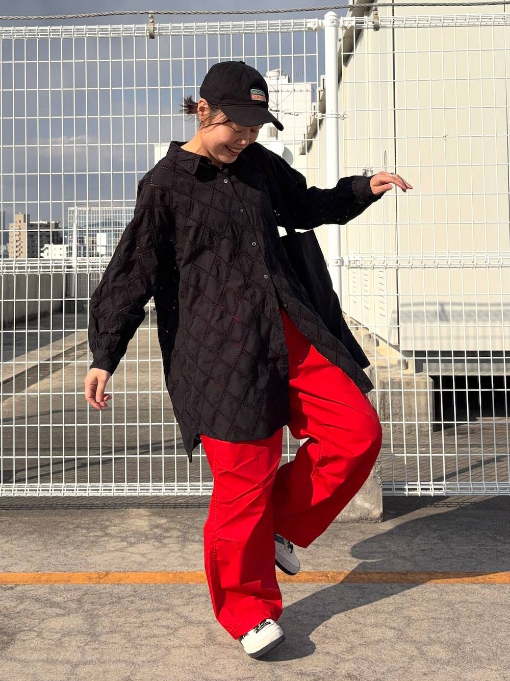 ブラック系のトートバッグ、ブラック系のチュニック、オレンジ系のその他パンツを着用したレディースの春コーディネートの1枚目の写真