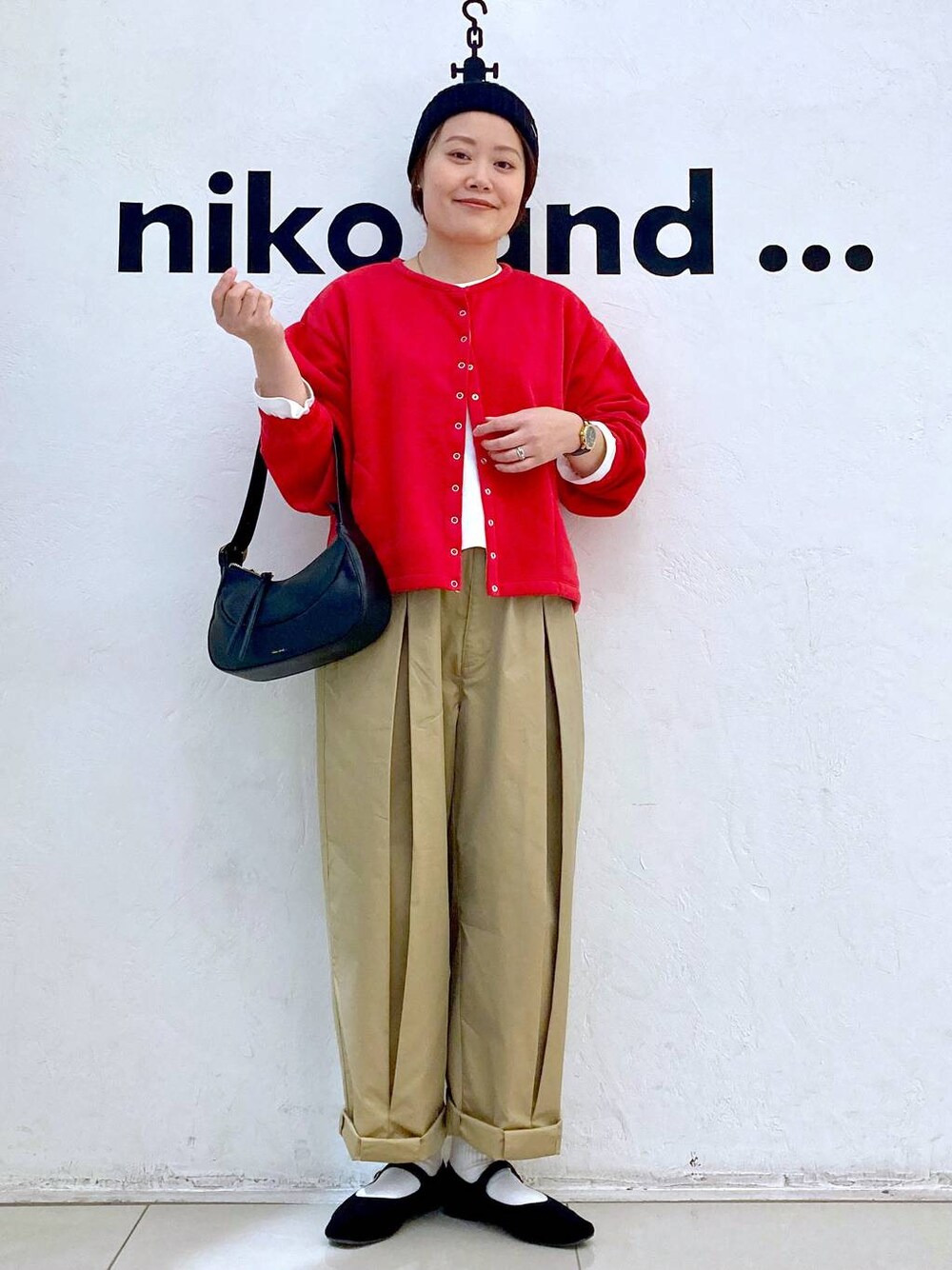 ブラック系のショルダーバッグ、ブラック系のパンプス、イエロー系のチノパンツを着用したレディースの冬コーディネートの1枚目の写真