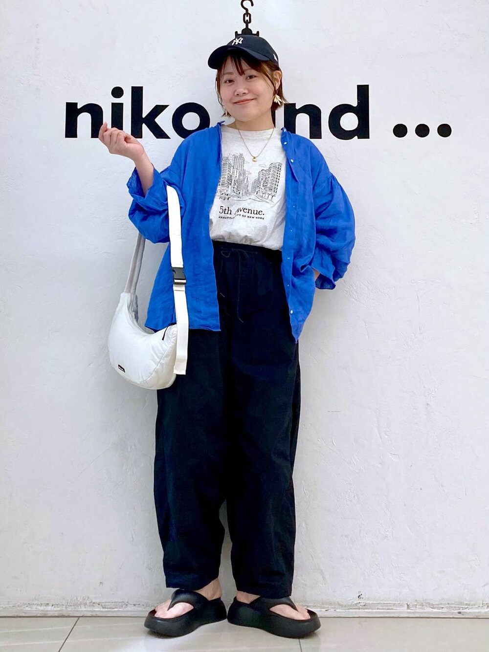 ブラック系のサンダル、ベージュ系のTシャツ/カットソー、ホワイト系のショルダーバッグを着用したレディースの春コーディネートの1枚目の写真