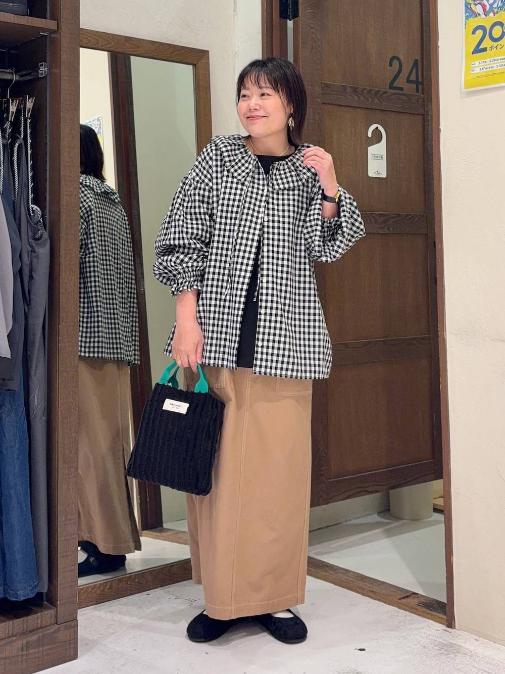 イエロー系のスカート、ブラック系のパンプス、ブラック系のトートバッグを着用したレディースの春コーディネートの1枚目の写真