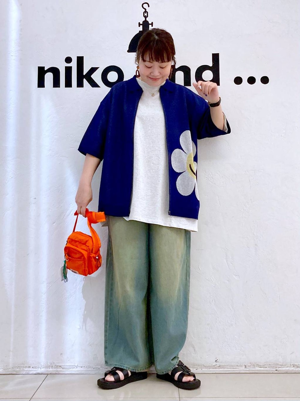 オレンジ系のショルダーバッグ、ベージュ系のTシャツ/カットソー、ブルー系のデニムパンツを着用したレディースの夏コーディネートの1枚目の写真