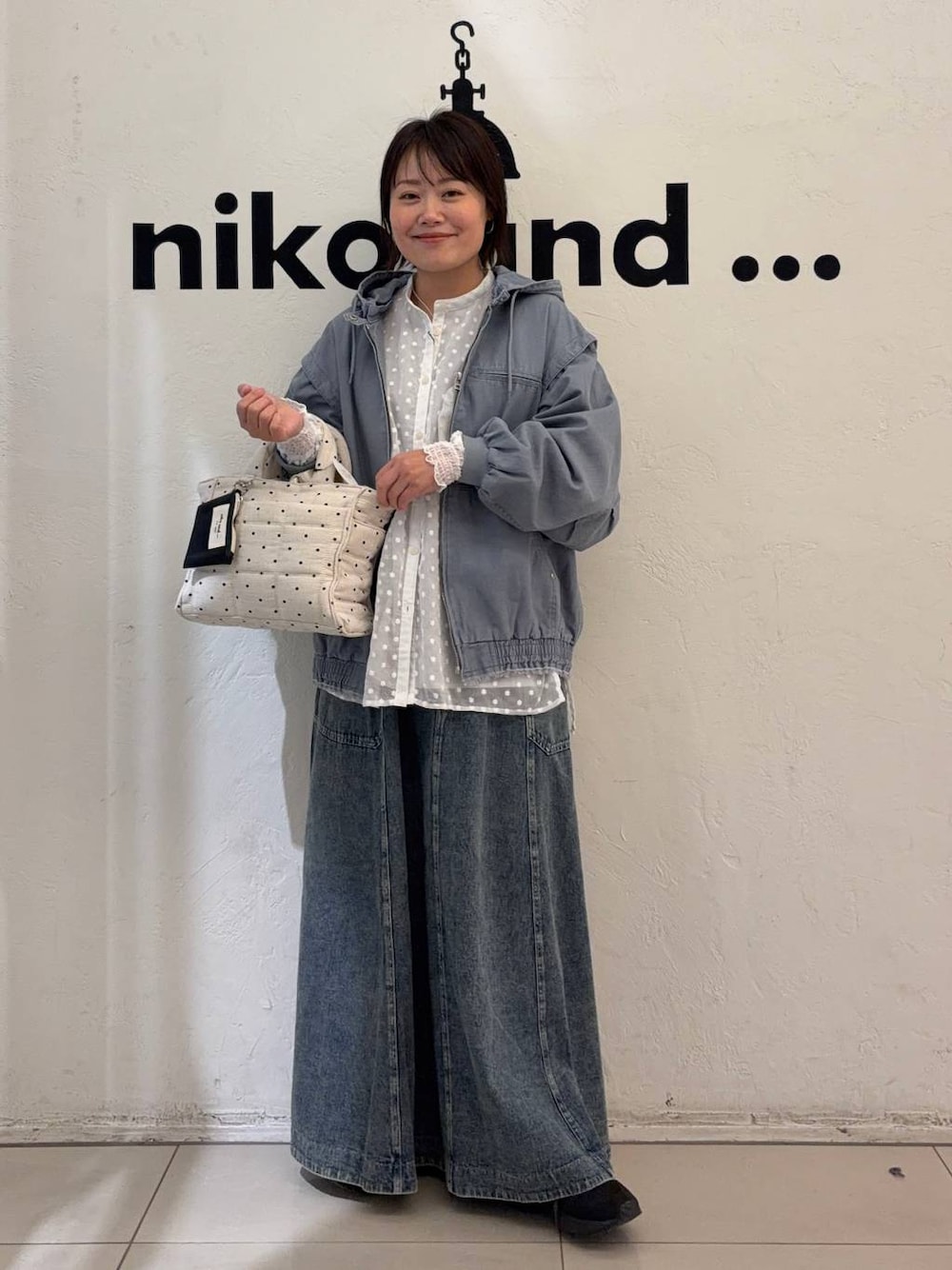 ブルー系のスカート、ホワイト系のトートバッグ、ブルー系のブルゾンを着用したレディースの冬コーディネートの1枚目の写真