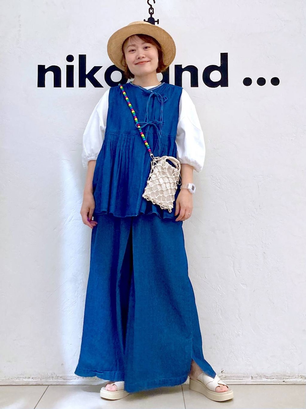 ベージュ系のショルダーバッグ、ベージュ系のサンダル、ホワイト系のTシャツ/カットソーを着用したレディースの夏コーディネートの1枚目の写真