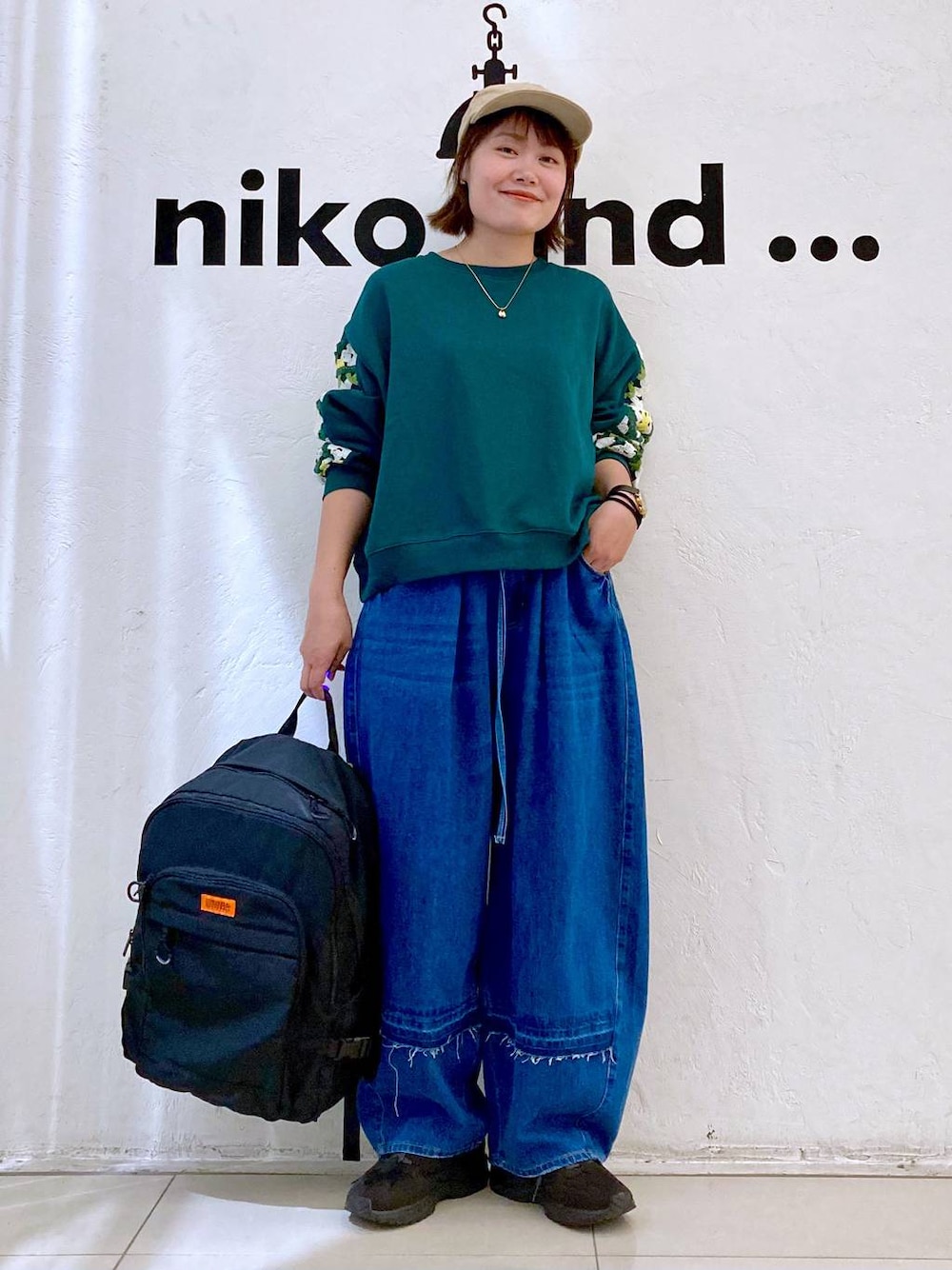 グリーン系のスウェット、ブルー系のデニムパンツ、ブラック系のバックパック/リュックを着用したレディースの秋コーディネートの1枚目の写真