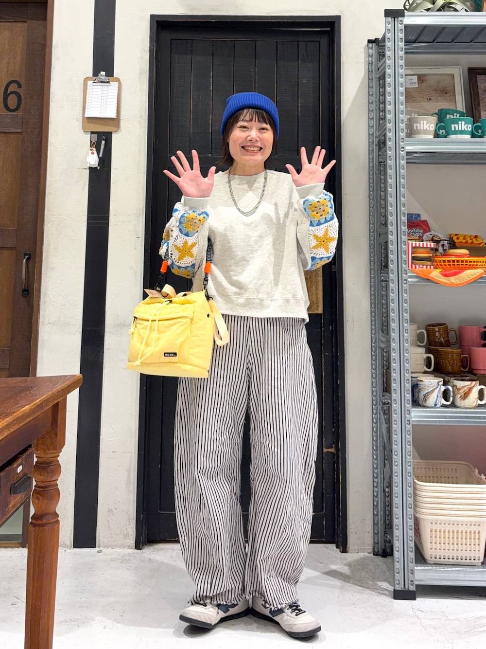 イエロー系のショルダーバッグ、ホワイト系のデニムパンツ、ブルー系のニットキャップ/ビーニーを着用したレディースの冬コーディネートの1枚目の写真