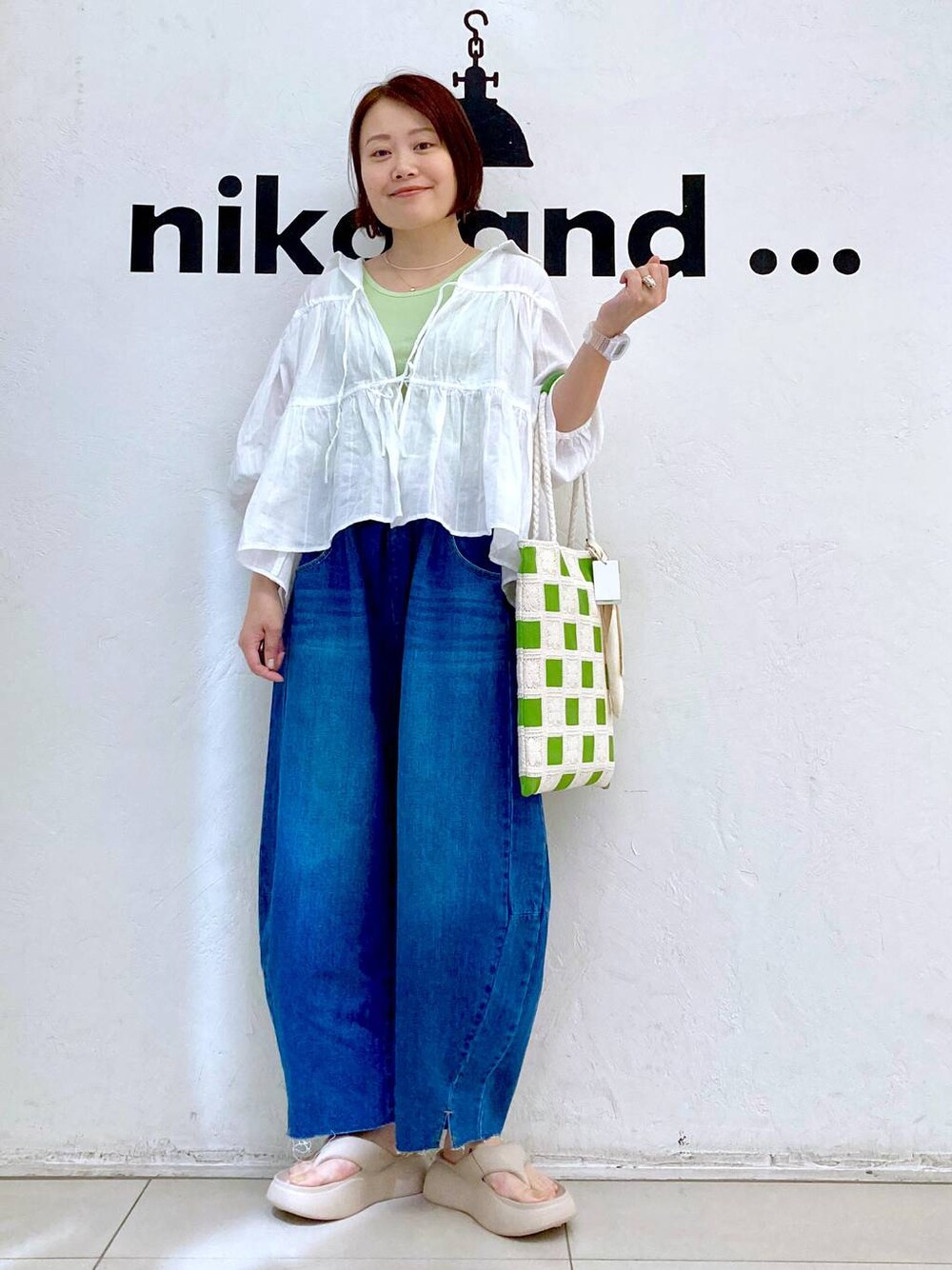 ベージュ系のサンダル、ブルー系のデニムパンツ、グリーン系のタンクトップを着用したレディースの夏コーディネートの1枚目の写真