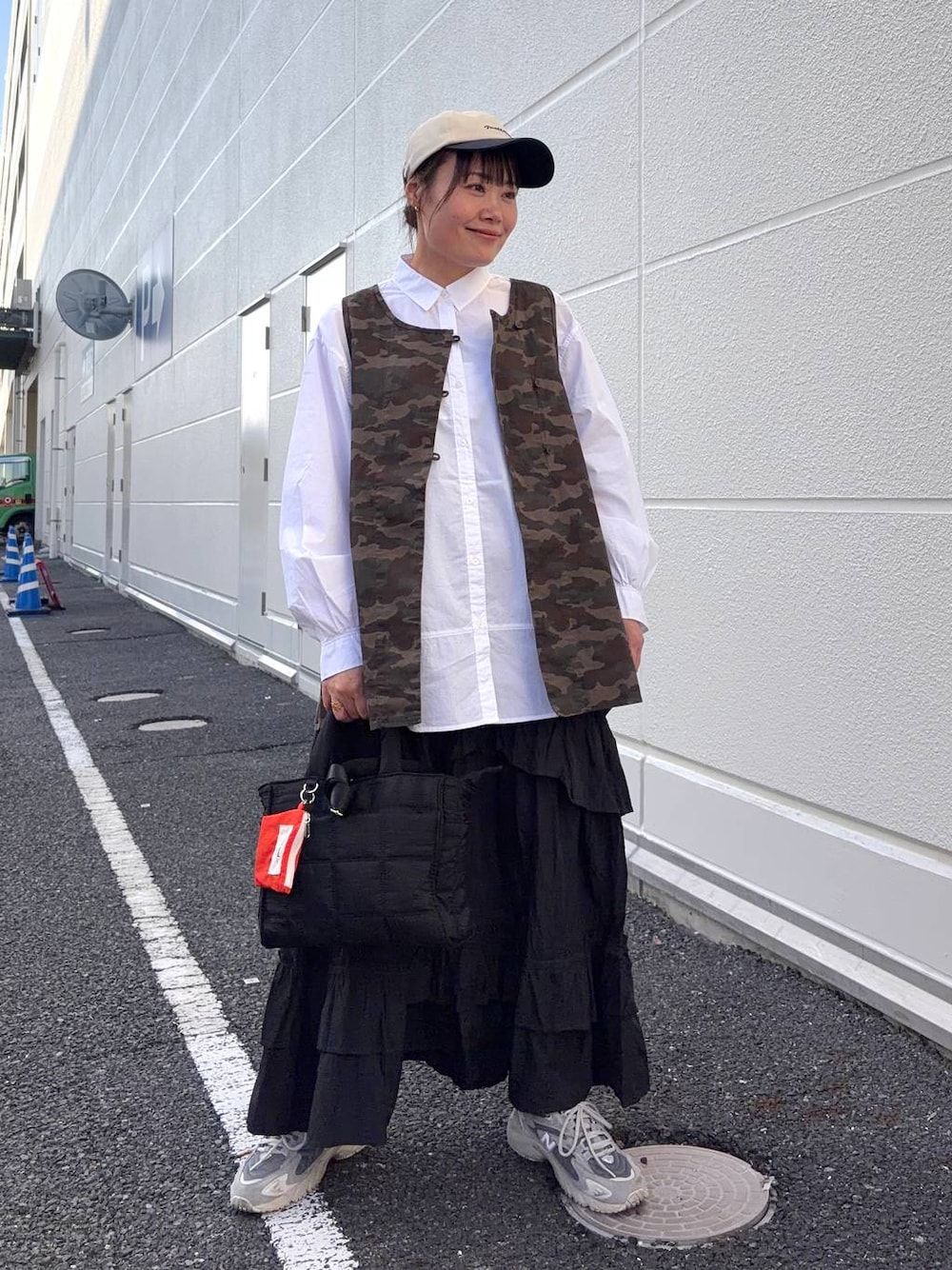 ブラック系のトートバッグ、ブラウン系のベスト、ホワイト系のシャツ/ブラウスを着用したレディースの春コーディネートの1枚目の写真