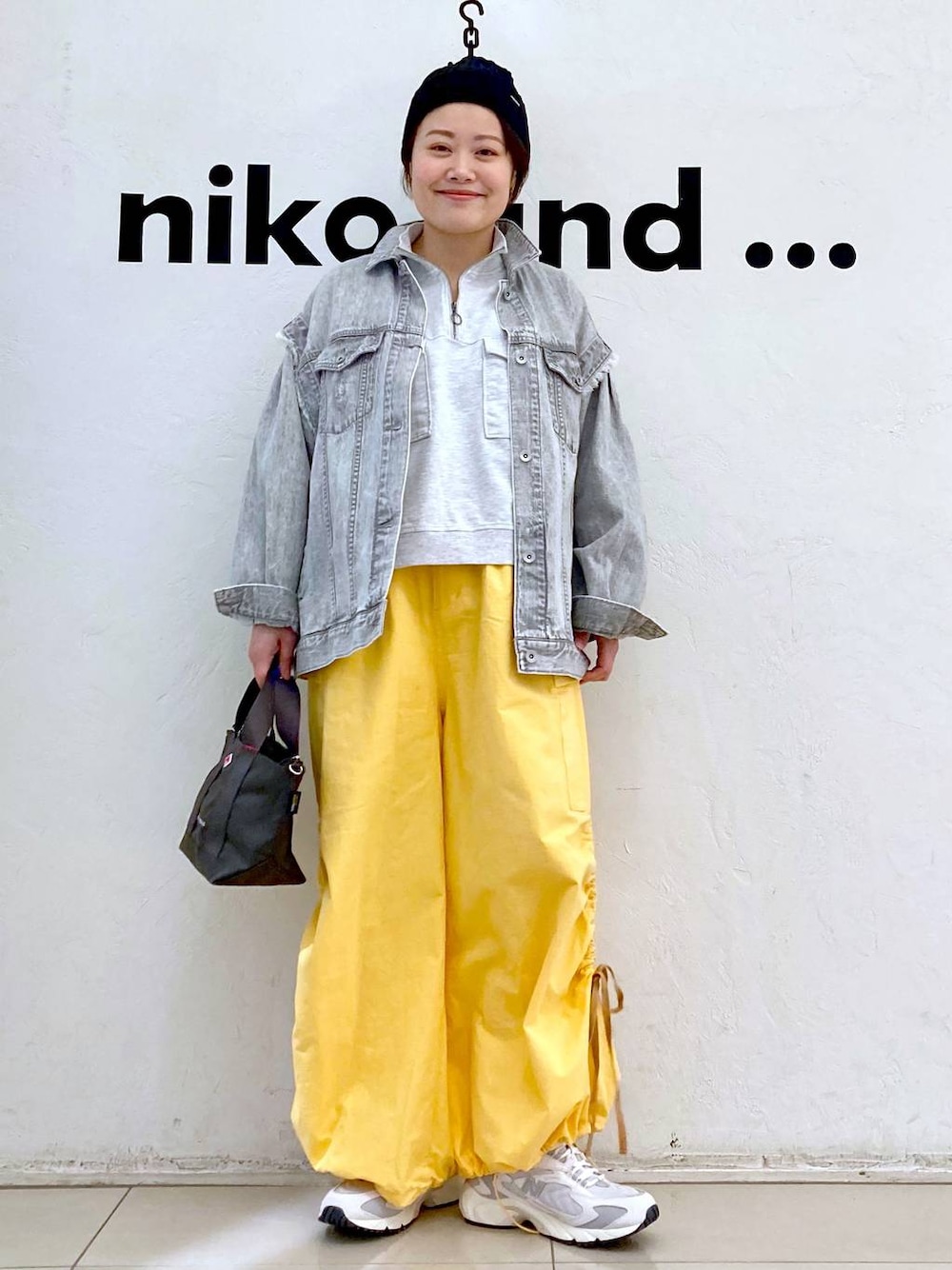 ベージュ系のスウェット、グレー系のデニムジャケット、ホワイト系のスニーカーを着用したレディースの冬コーディネートの1枚目の写真