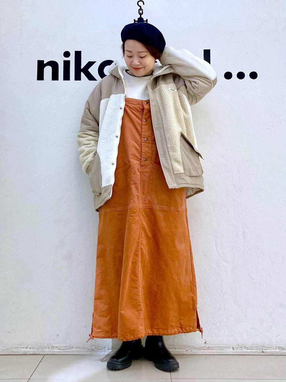 ベージュ系のその他アウター、ホワイト系のニット/セーター、ブラック系のブーツを着用したレディースの冬コーディネートの1枚目の写真