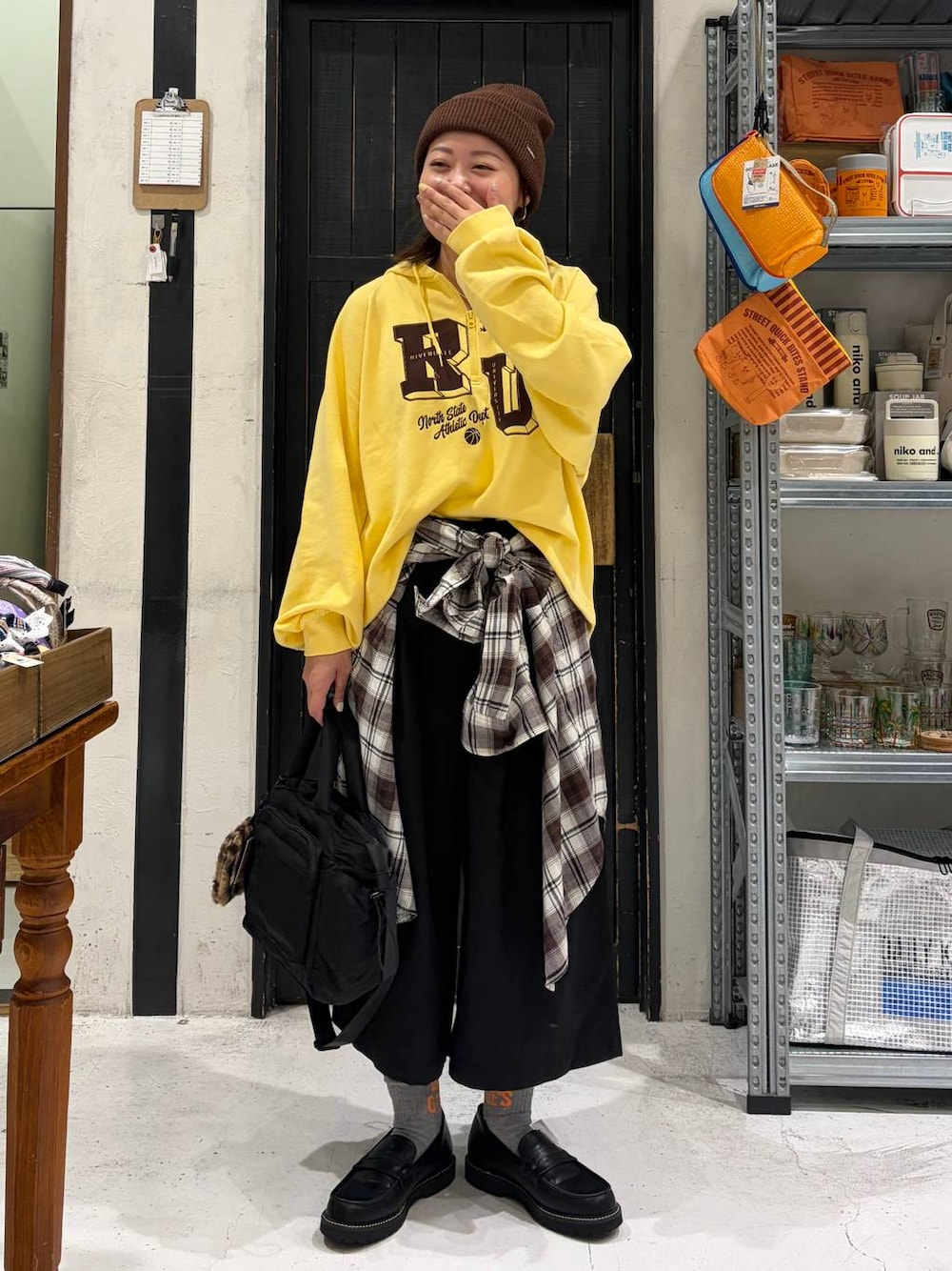 イエロー系のパーカー、ブラック系のその他パンツ、ブラック系のトートバッグを着用したレディースの秋コーディネートの1枚目の写真