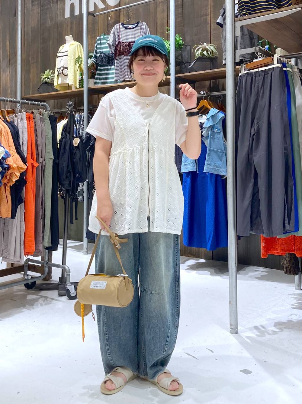 ブルー系のその他パンツ、ホワイト系のベスト、ベージュ系のショルダーバッグを着用したレディースの夏コーディネートの1枚目の写真