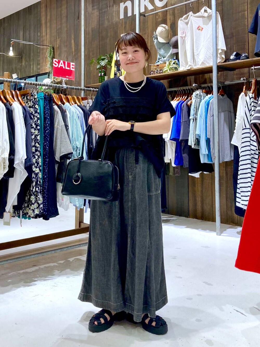 グレー系のスカート、ブラック系のボストンバッグ、ブラック系のTシャツ/カットソーを着用したレディースの夏コーディネートの1枚目の写真