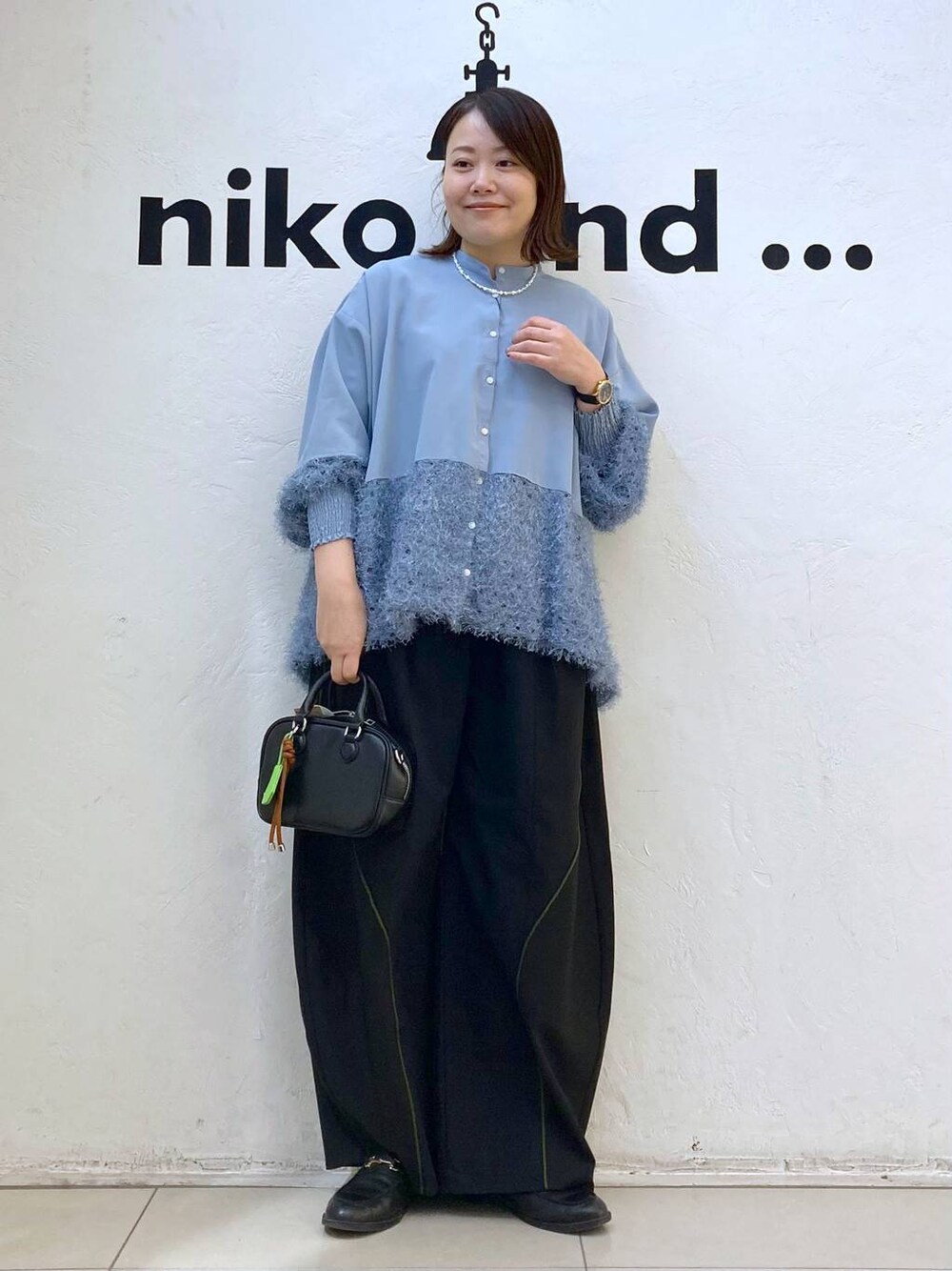 ブラック系のボストンバッグ、ブルー系のシャツ/ブラウス、シルバー系のピアス(両耳用)を着用したレディースの冬コーディネートの1枚目の写真