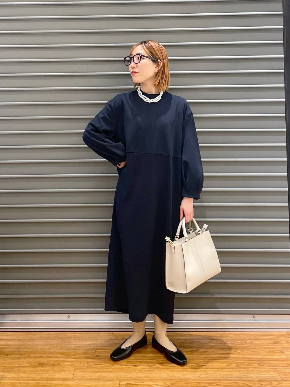 ブラック系のパンプス、ブルー系のワンピース、ホワイト系のショルダーバッグを着用したレディースの冬コーディネートの1枚目の写真