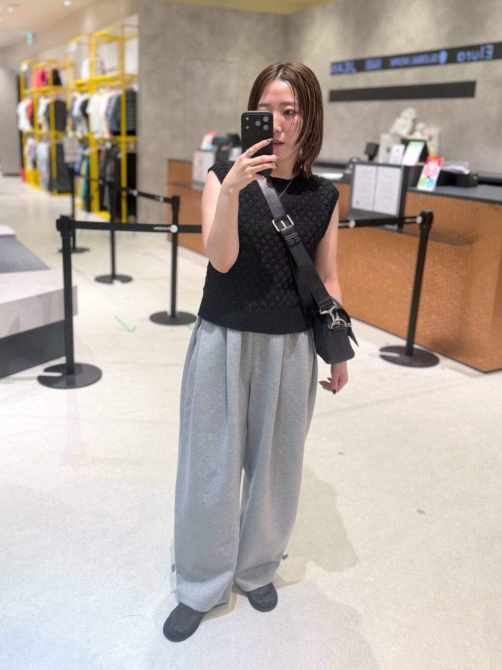 グレー系のスウェットパンツ、ブラック系のベスト、ブラック系のショルダーバッグを着用したレディースの夏コーディネートの1枚目の写真
