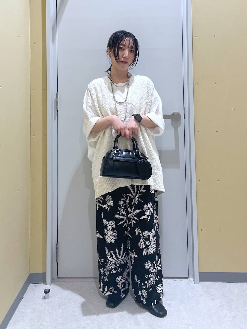 ホワイト系のニット/セーター、ホワイト系のTシャツ/カットソー、ブラック系のショルダーバッグを着用したレディースの春コーディネートの1枚目の写真