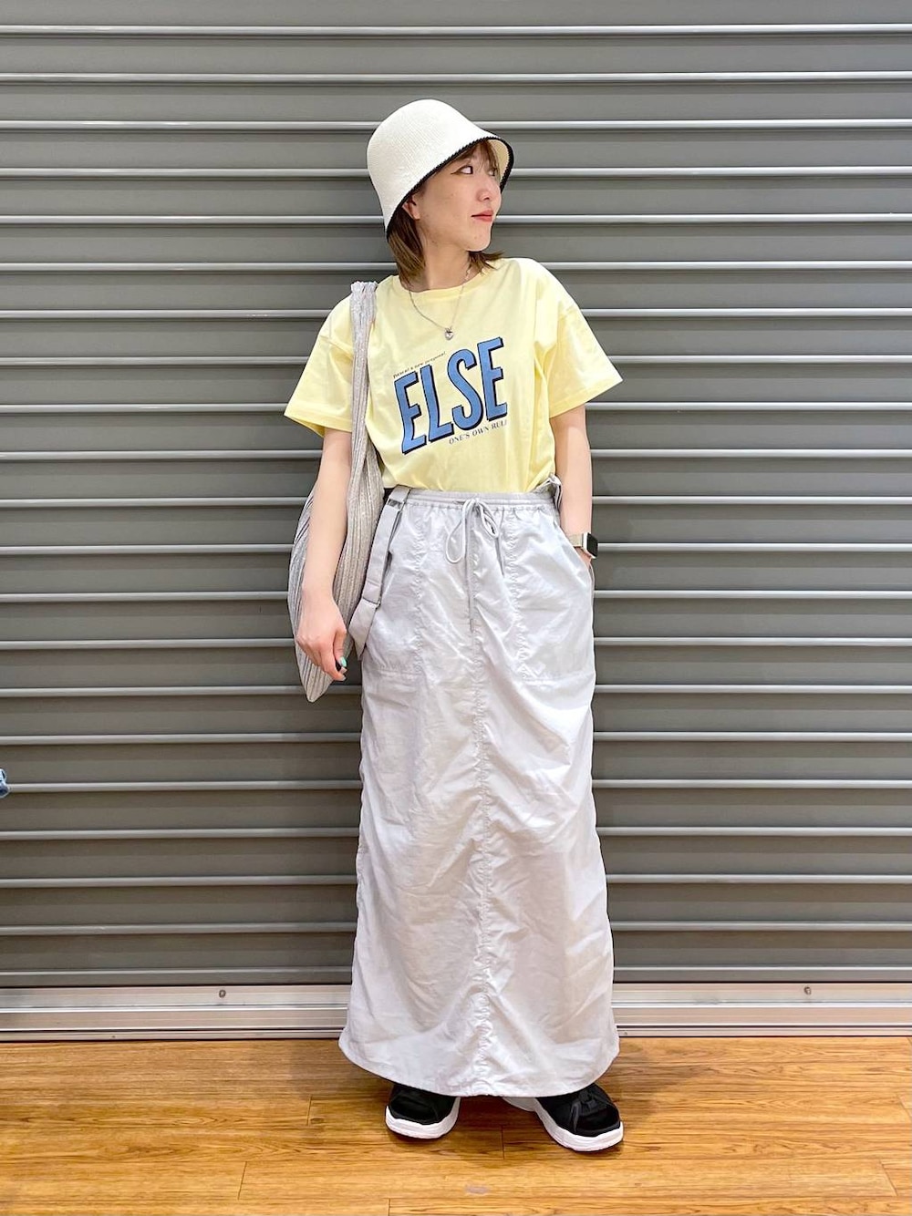 ブラック系のサンダル、グレー系のスカート、イエロー系のTシャツ/カットソーを着用したレディースの春コーディネートの1枚目の写真