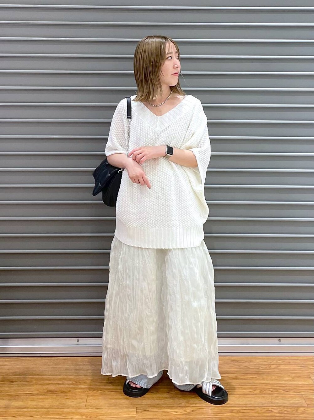 ブラック系のショルダーバッグ、ブルー系のデニムパンツ、シルバー系のサンダルを着用したレディースの夏コーディネートの1枚目の写真