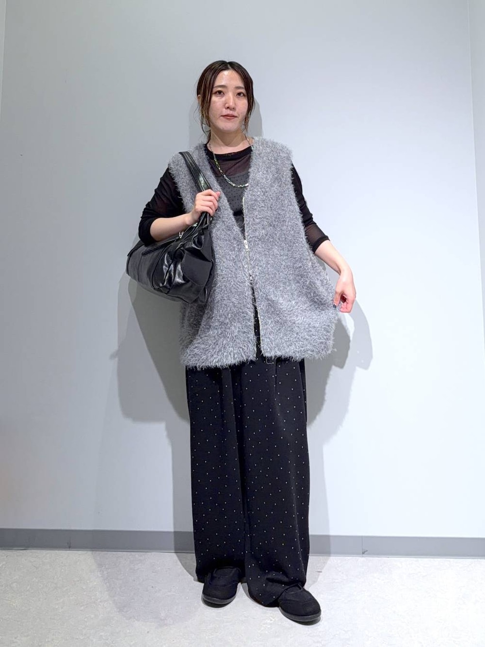 ブラック系のパンプス、ブラック系のトートバッグ、グレー系のベストを着用したレディースの秋コーディネートの1枚目の写真