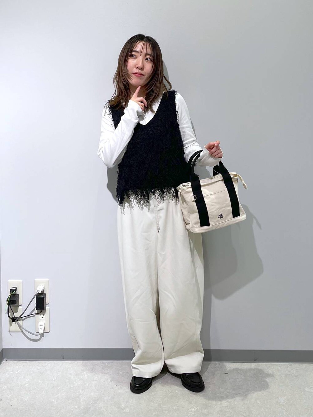 ホワイト系のトートバッグ、ホワイト系のその他パンツ、ブラック系のベストを着用したレディースの春コーディネートの1枚目の写真