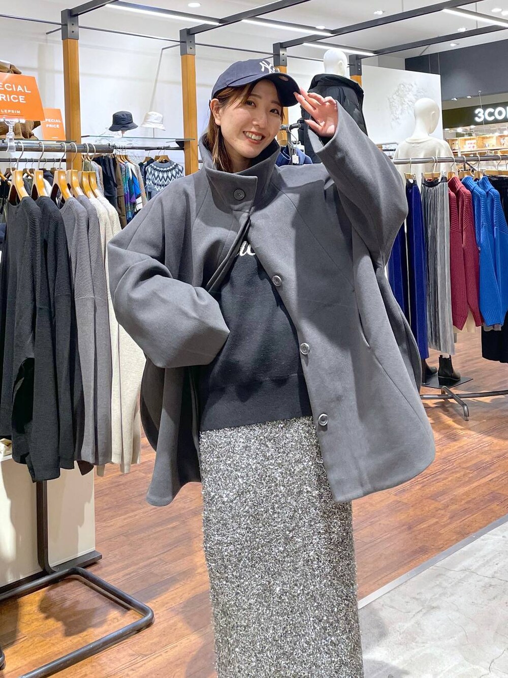 グレー系のポンチョ、ブラック系のニット/セーター、ブラック系のスカートを着用したレディースの冬コーディネートの1枚目の写真