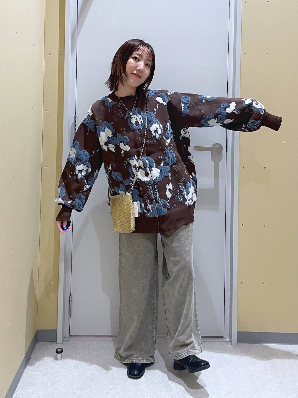 ゴールド系のショルダーバッグ、ブラウン系のカーディガン/ボレロ、グレー系のスウェットパンツを着用したレディースの秋コーディネートの1枚目の写真