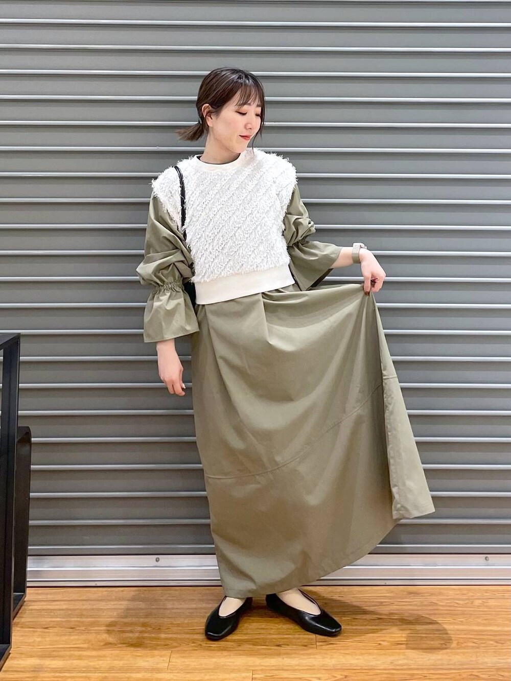 ホワイト系のベスト、ブラック系のパンプス、グリーン系のワンピースを着用したレディースの春コーディネートの1枚目の写真