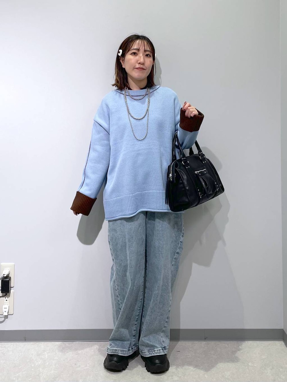 ブラック系のボストンバッグ、ブルー系のデニムパンツ、ブルー系のニット/セーターを着用したレディースの冬コーディネートの1枚目の写真