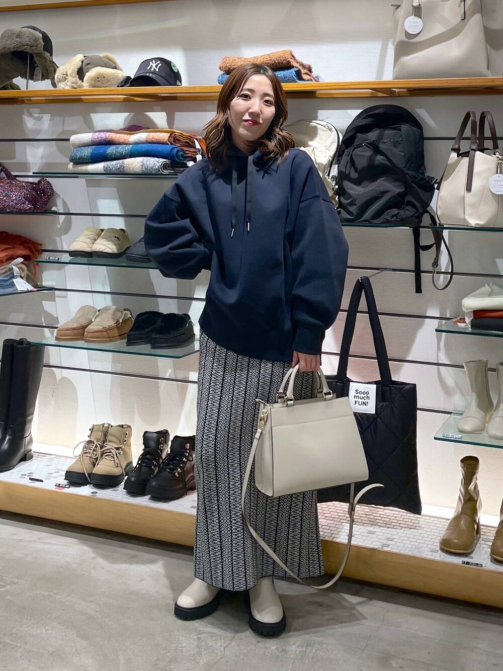 ホワイト系のブーツ、ブラック系のスカート、ブルー系のパーカーを着用したレディースの冬コーディネートの1枚目の写真