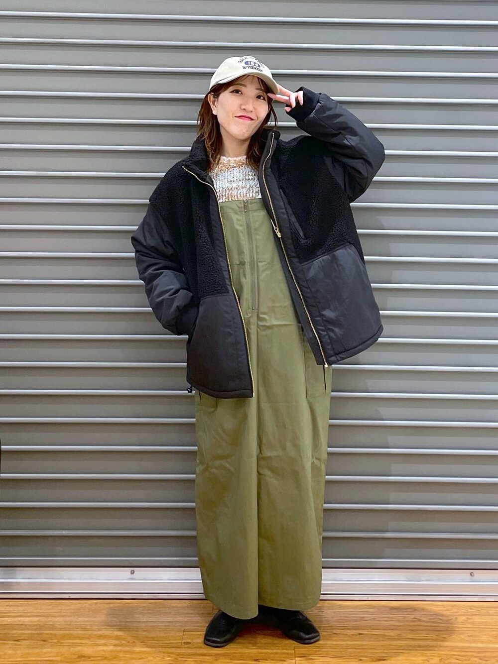 ブラック系のその他アウター、グリーン系のジャンパースカート、ベージュ系のニット/セーターを着用したレディースの冬コーディネートの1枚目の写真