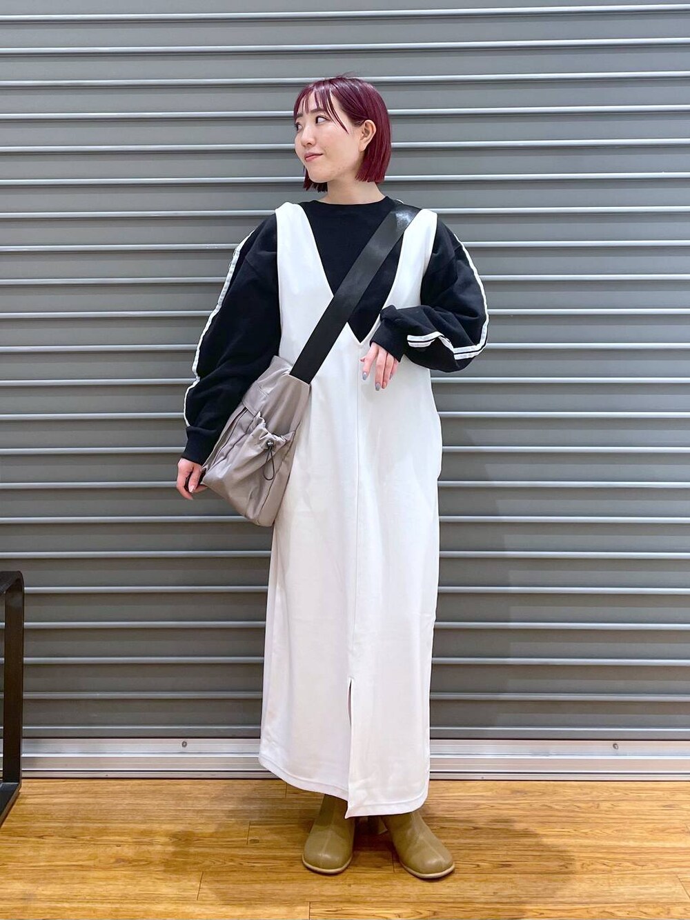 ブラウン系のブーツ、ホワイト系のジャンパースカート、ブラック系のTシャツ/カットソーを着用したレディースの冬コーディネートの1枚目の写真
