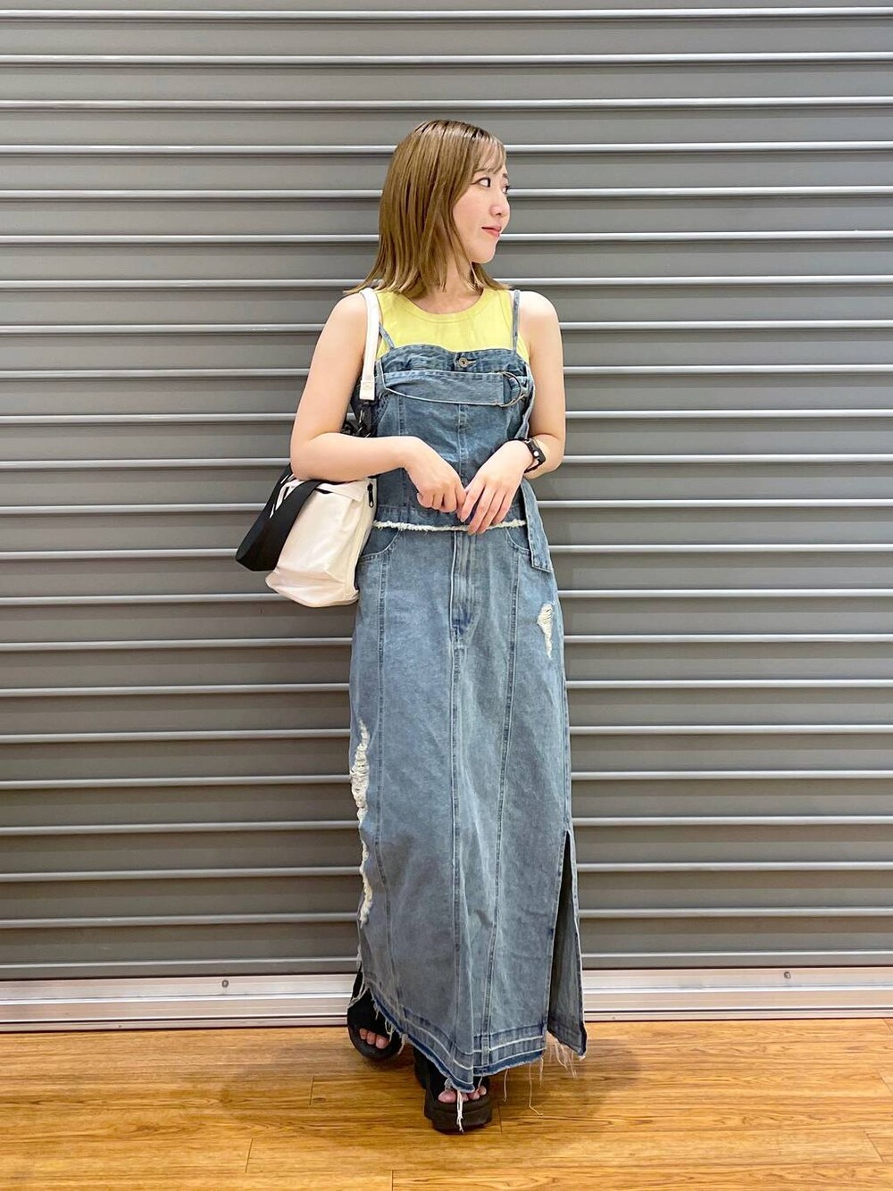 ホワイト系のショルダーバッグ、ブルー系のスカート、ブルー系のベストを着用したレディースの夏コーディネートの1枚目の写真