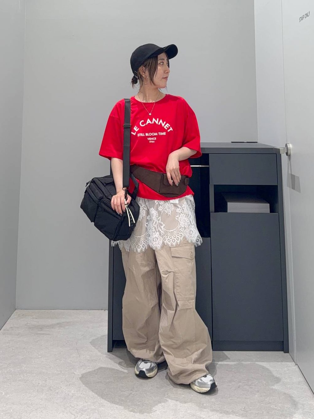 ベージュ系のカーゴパンツ、ブラック系のボストンバッグ、レッド系のTシャツ/カットソーを着用したレディースの夏コーディネートの1枚目の写真
