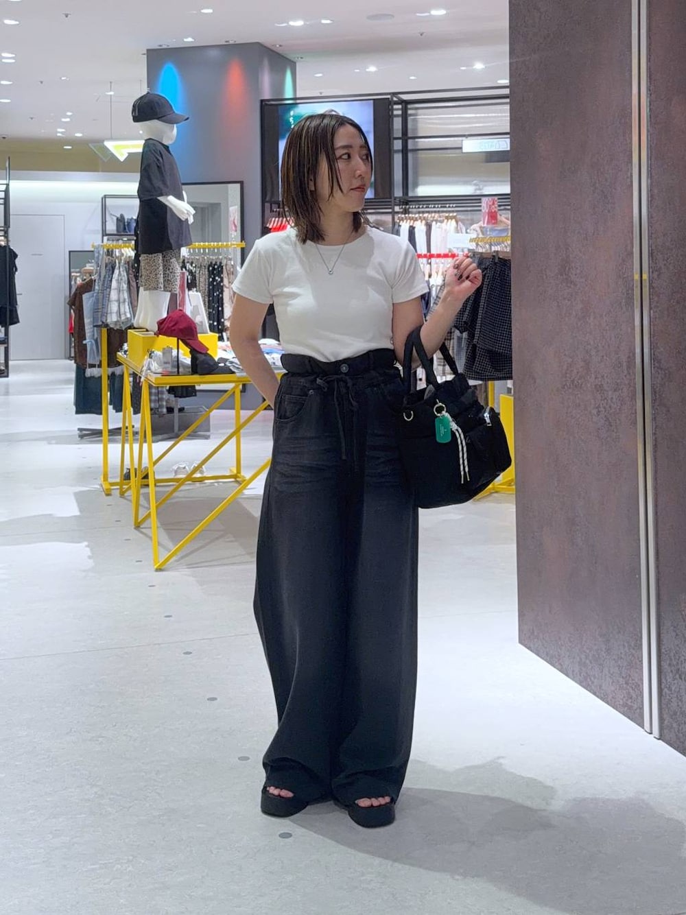 ブラック系のデニムパンツ、ブラック系のトートバッグ、シルバー系のサンダルを着用したレディースの夏コーディネートの1枚目の写真