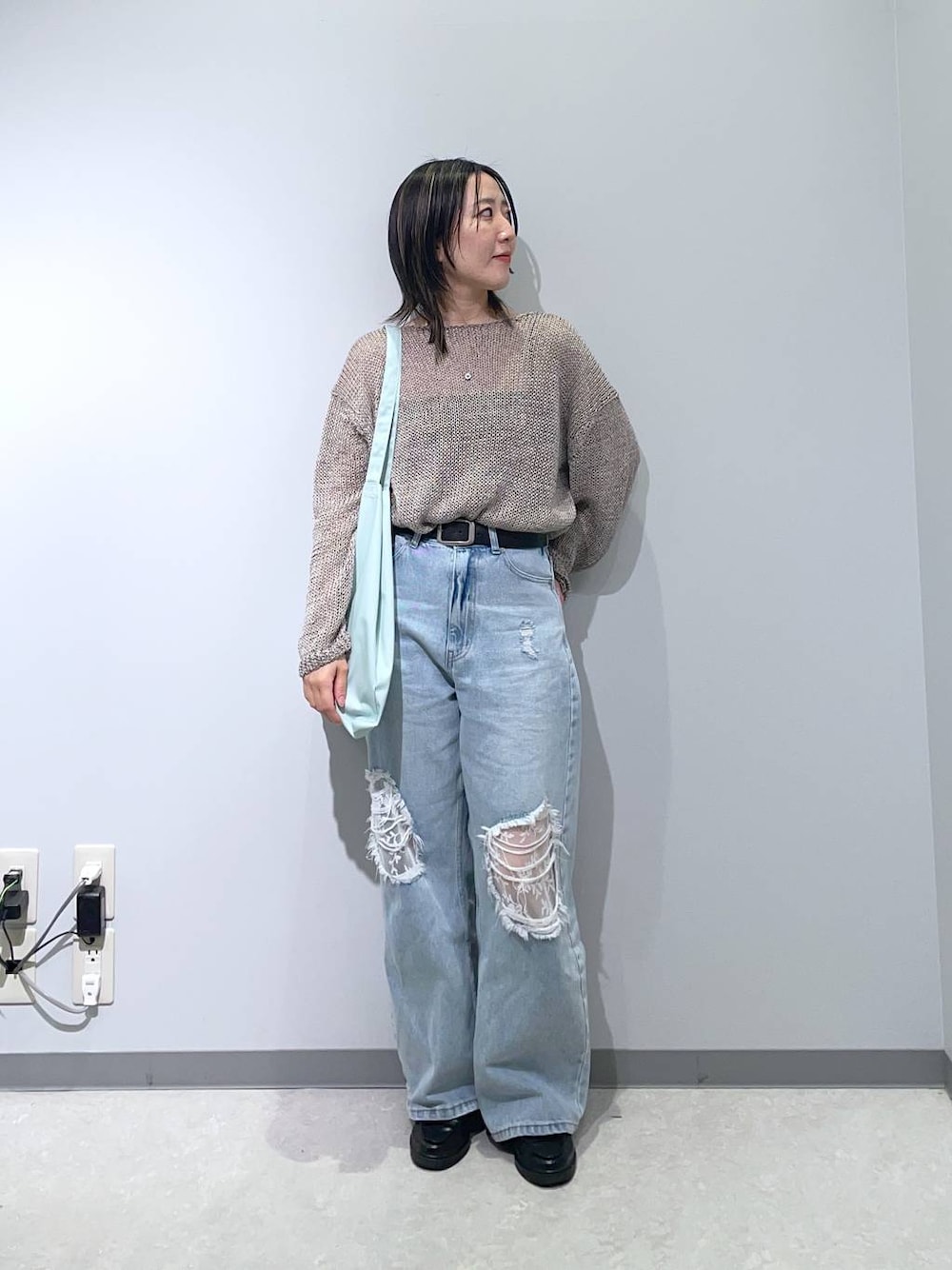 ブルー系のデニムパンツ、グレー系のニット/セーターを着用したレディースの春コーディネートの1枚目の写真