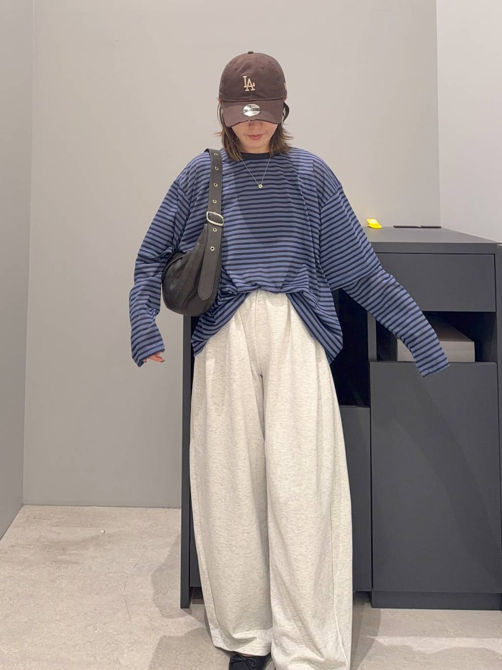 ブラック系のショルダーバッグ、ブルー系のTシャツ/カットソー、ベージュ系のスウェットパンツを着用したレディースの夏コーディネートの1枚目の写真