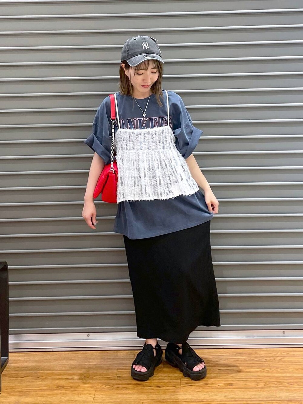 レッド系のショルダーバッグ、ブルー系のTシャツ/カットソー、ブラック系のスカートを着用したレディースの夏コーディネートの1枚目の写真